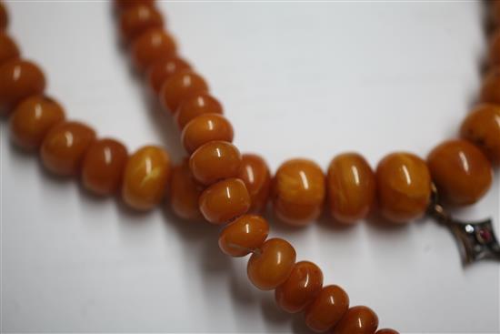 A single strand graduated disc shaped amber bead necklace with rose cut diamond and ruby set amber drop pendant, gross weight